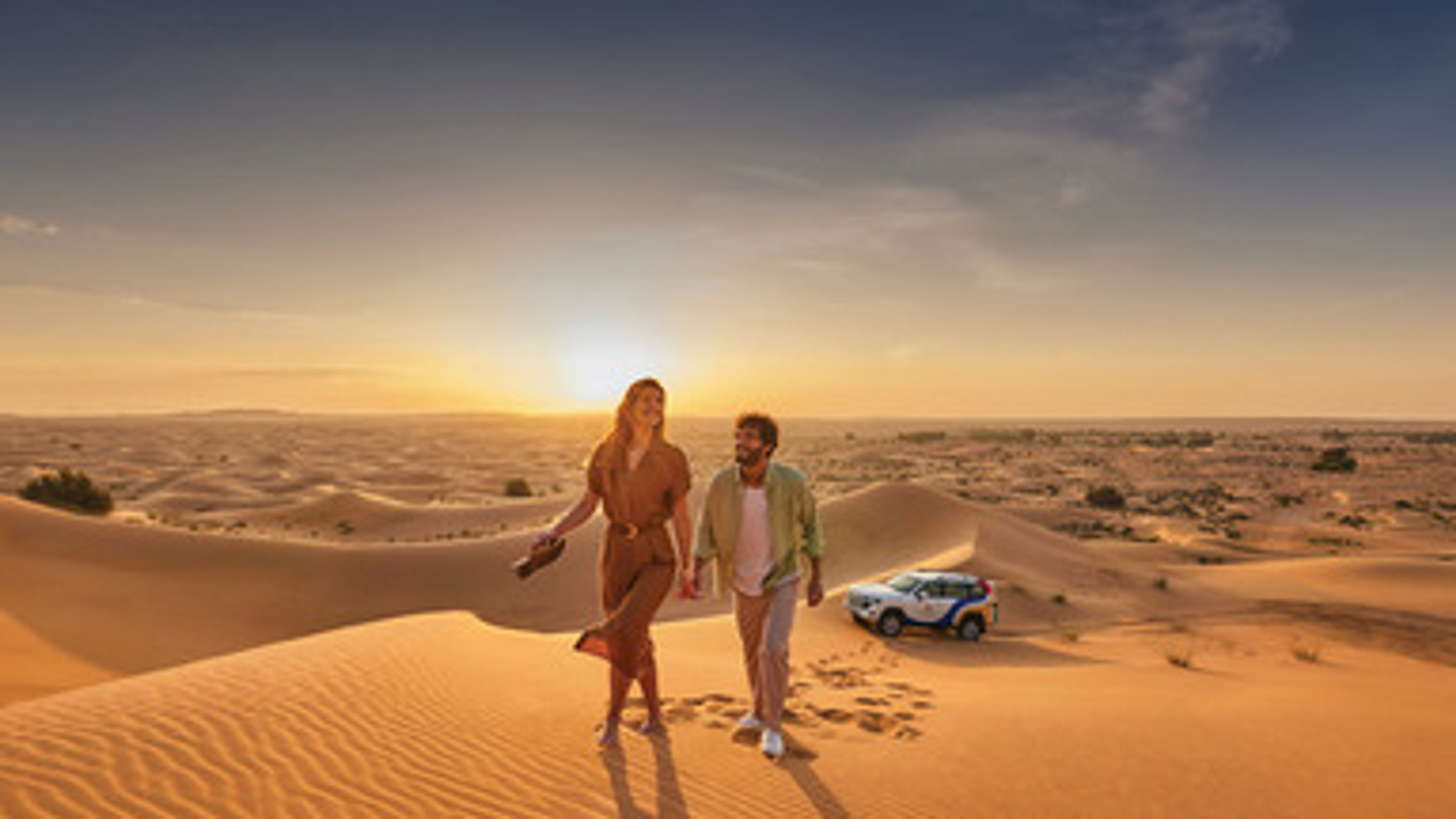 A couple walking in a desert with a car parked at backside.