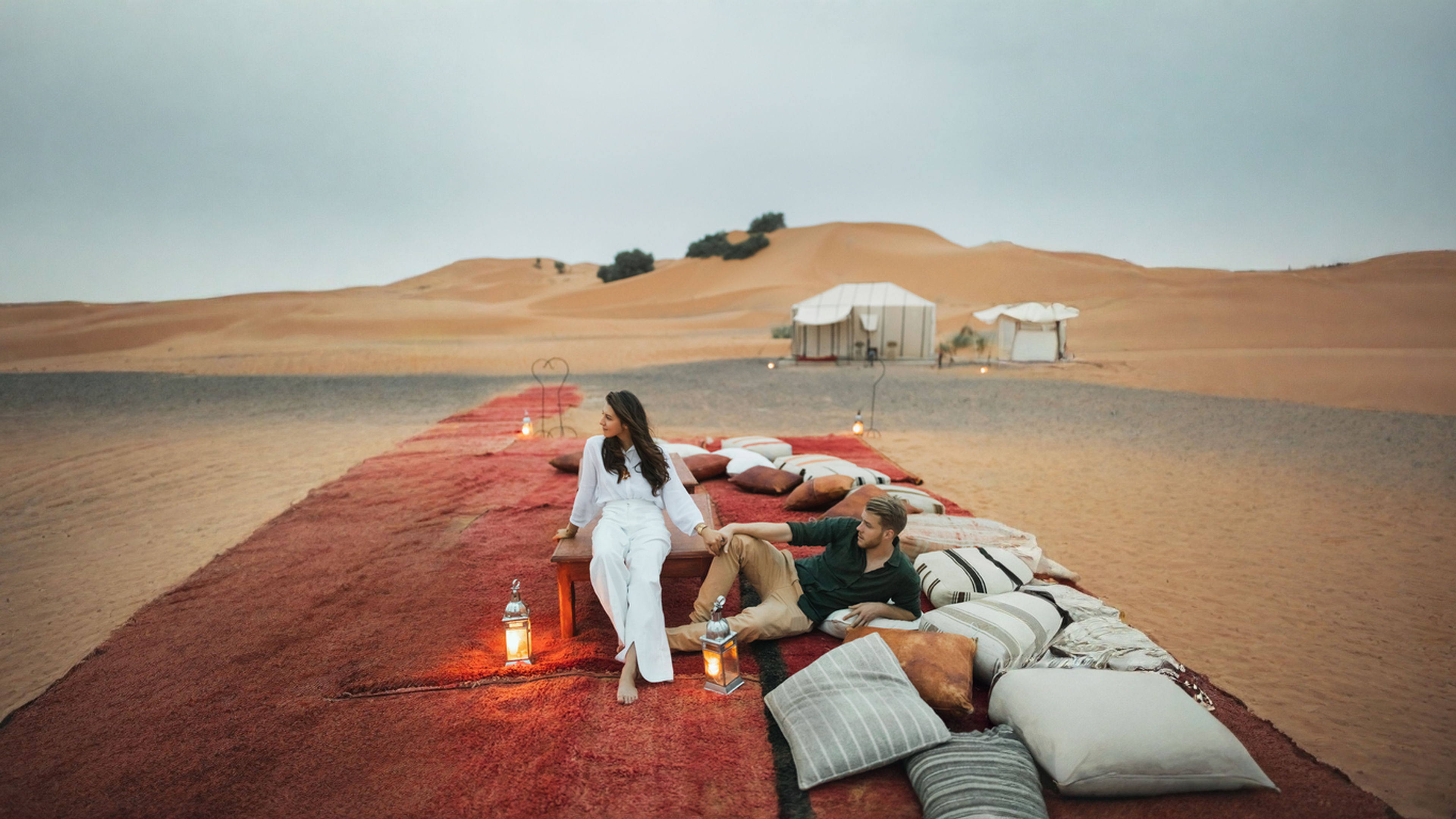 Stylish couple in love enjoying evening together in luxury glamping camp in Sahara desert.