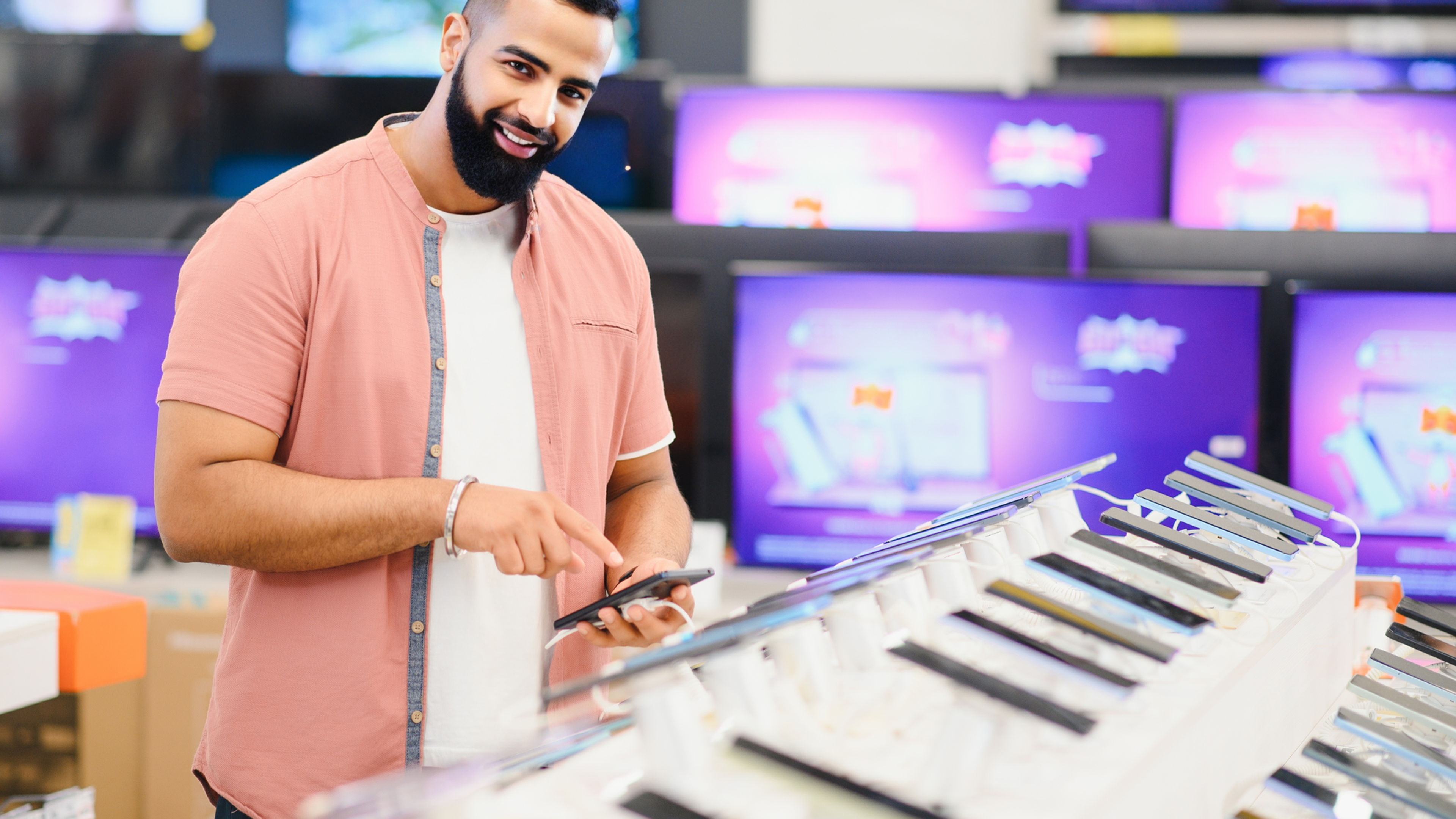 Handsome young man checking new mobile in the electronic shop.