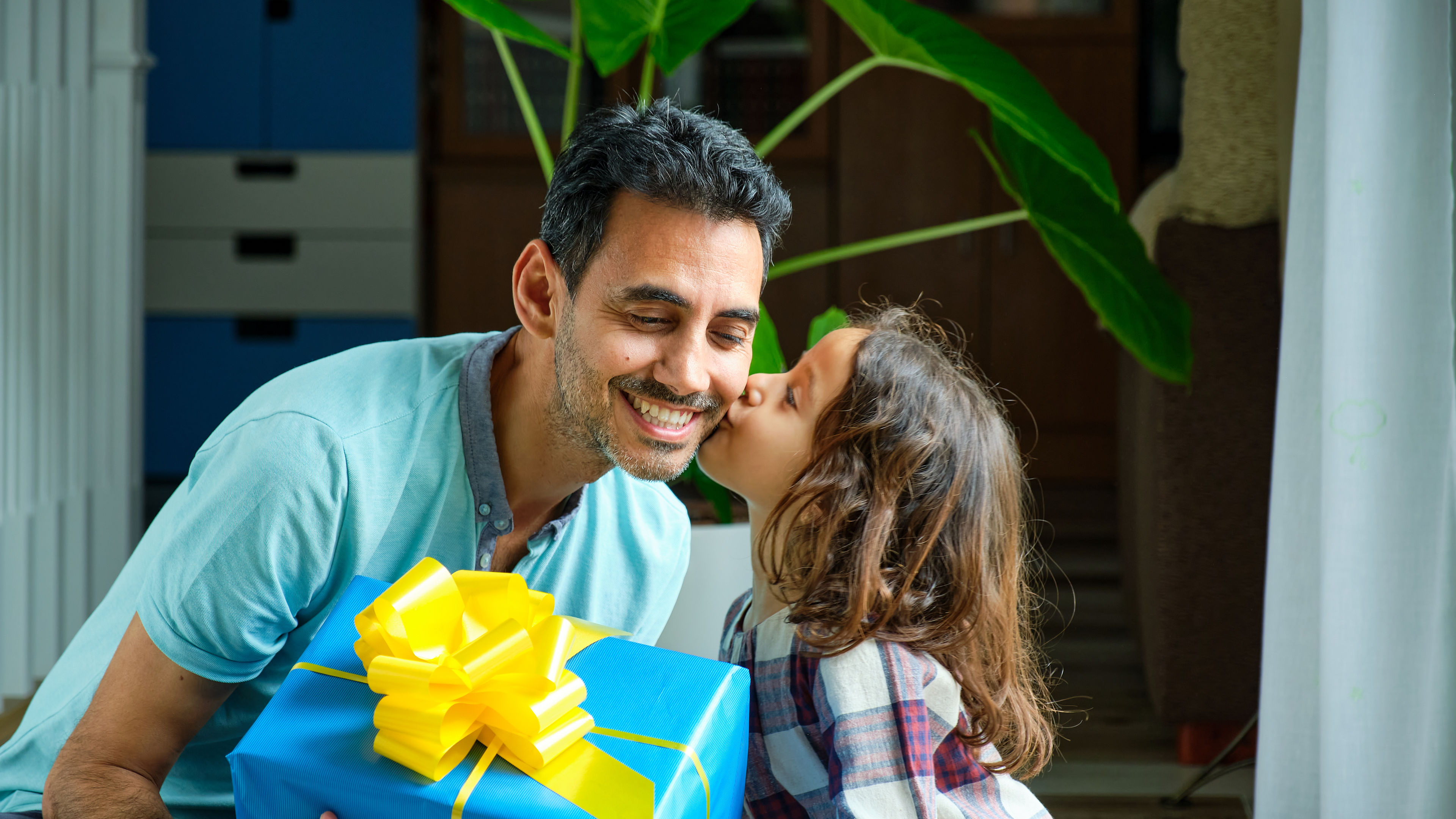 A girl giving a kiss and gift to her father