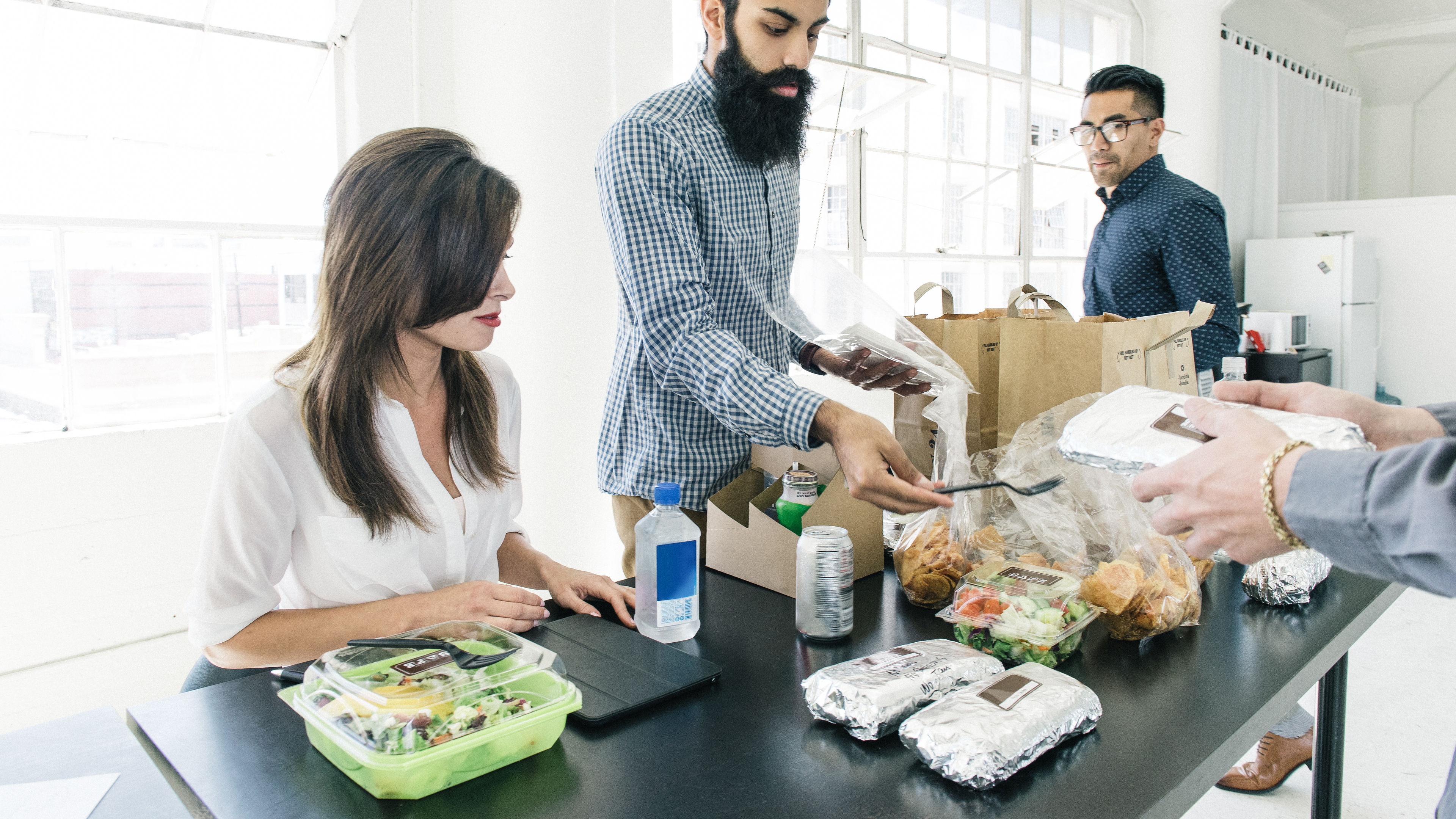 A group of coworkers are gathered around a black office table