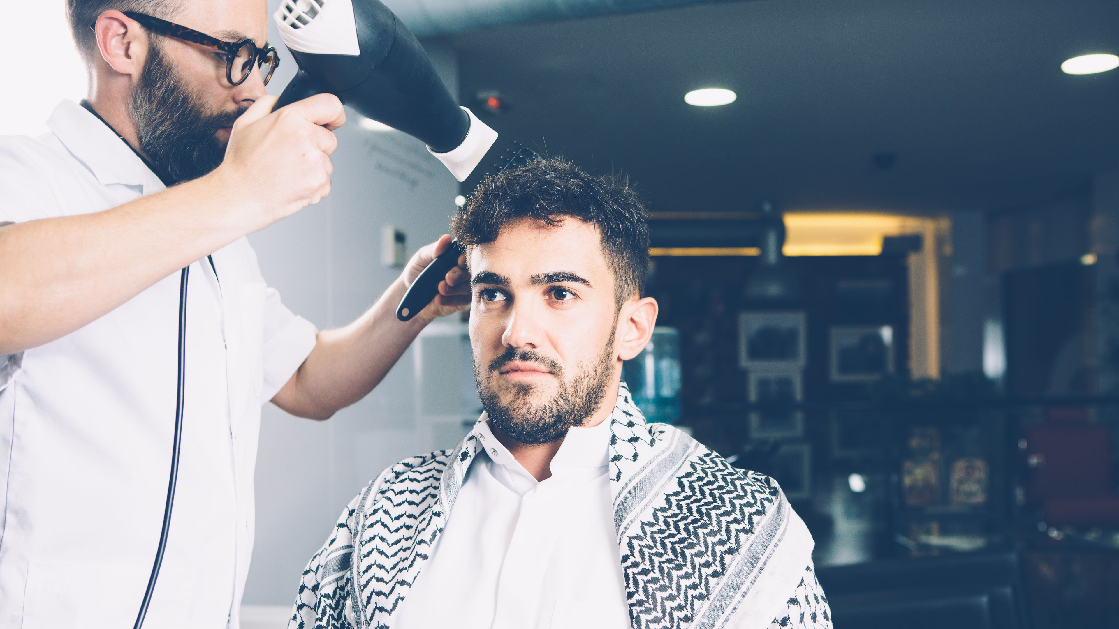 A man getting his hair styled at a barber shop 