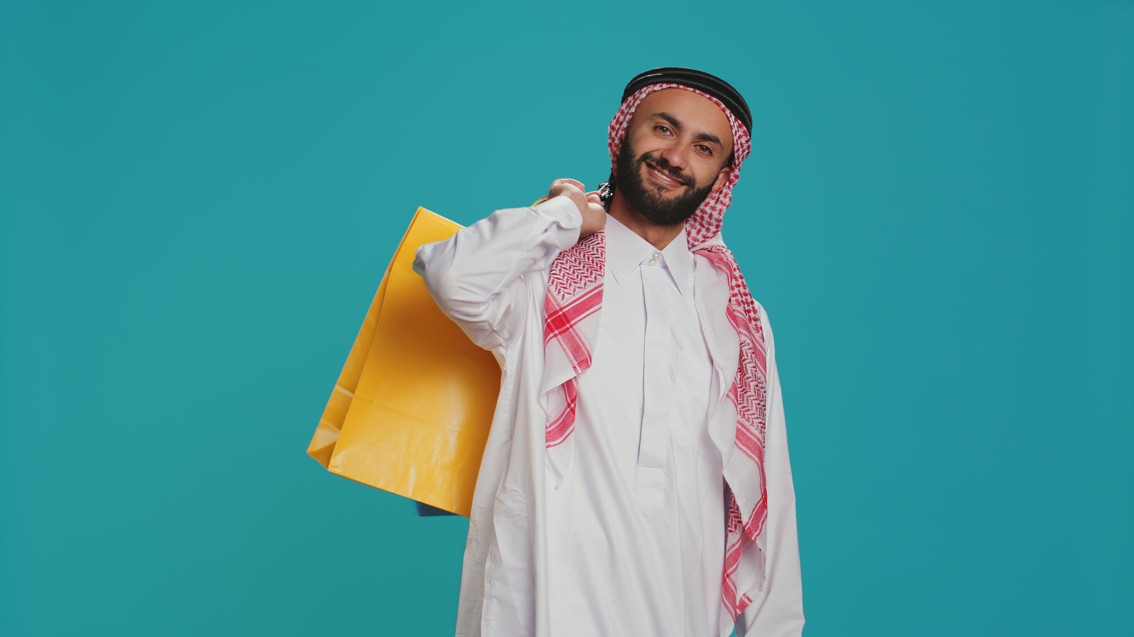 A smiling man holding a bright yellow shopping bag