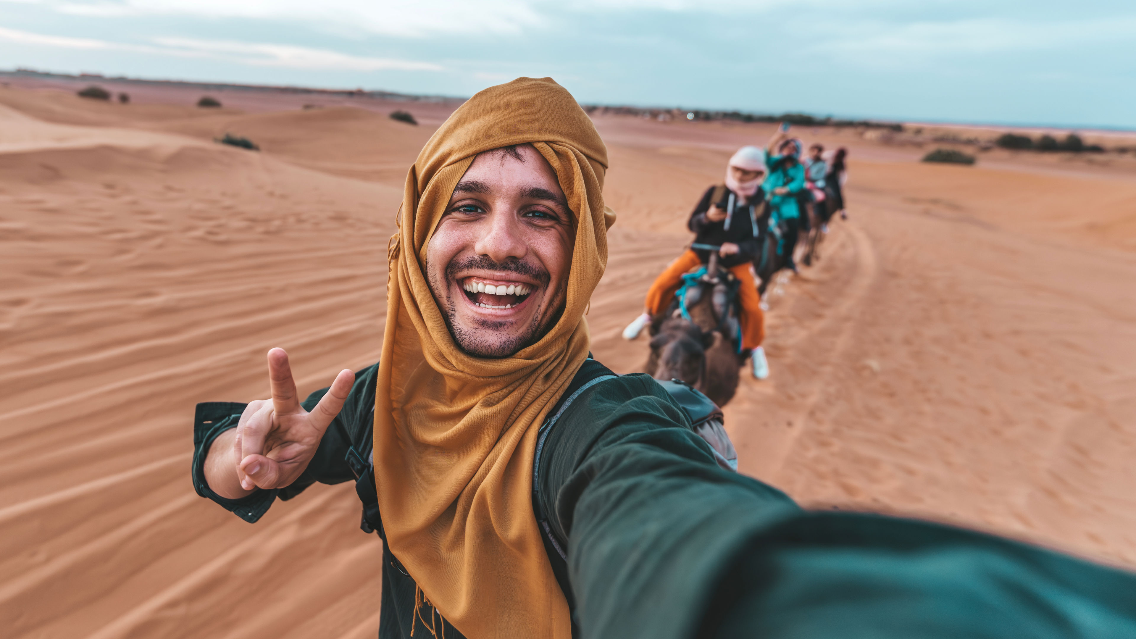Happy tourist having fun enjoying group camel ride