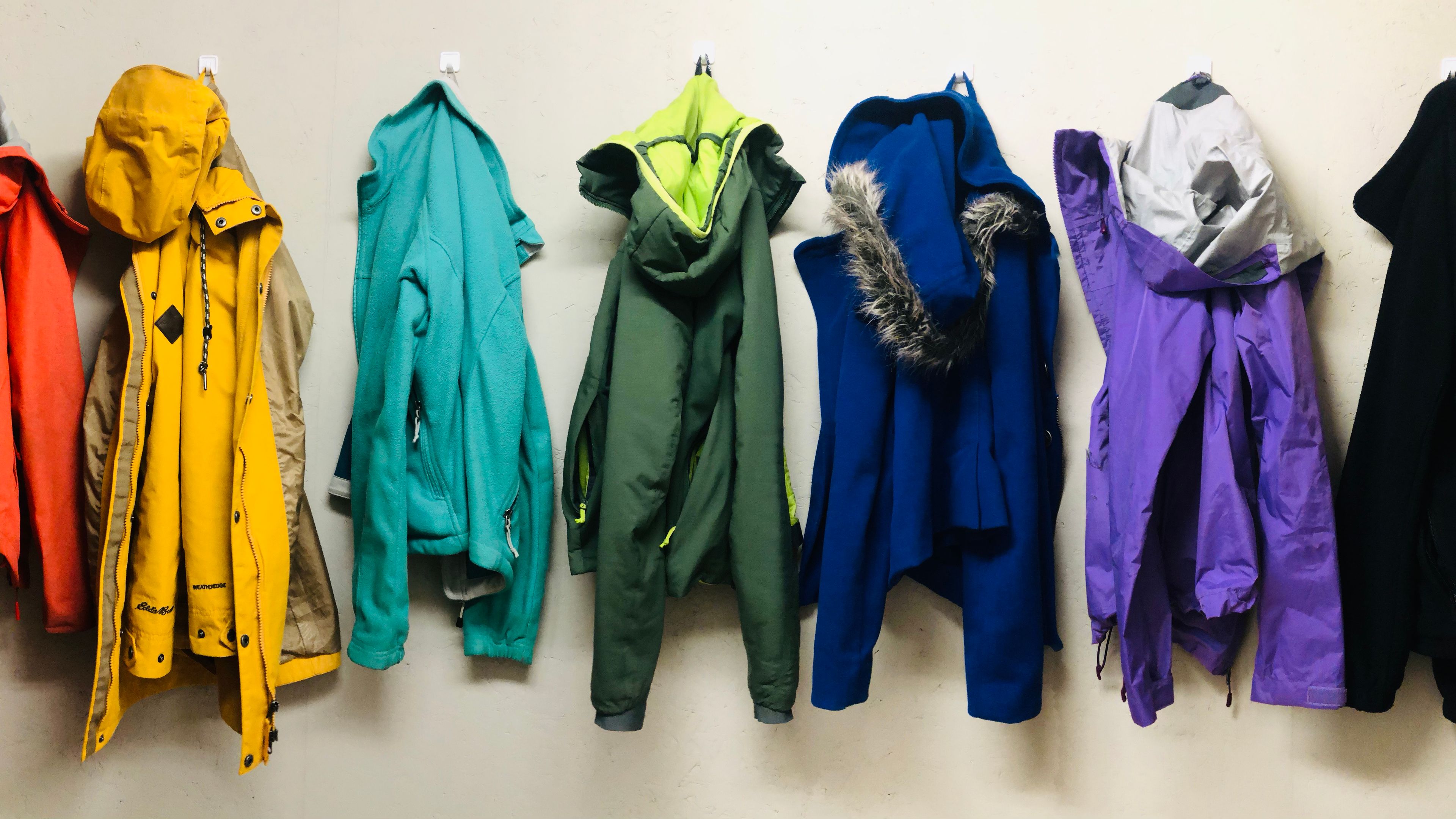 Rainbow jackets hung up on wall