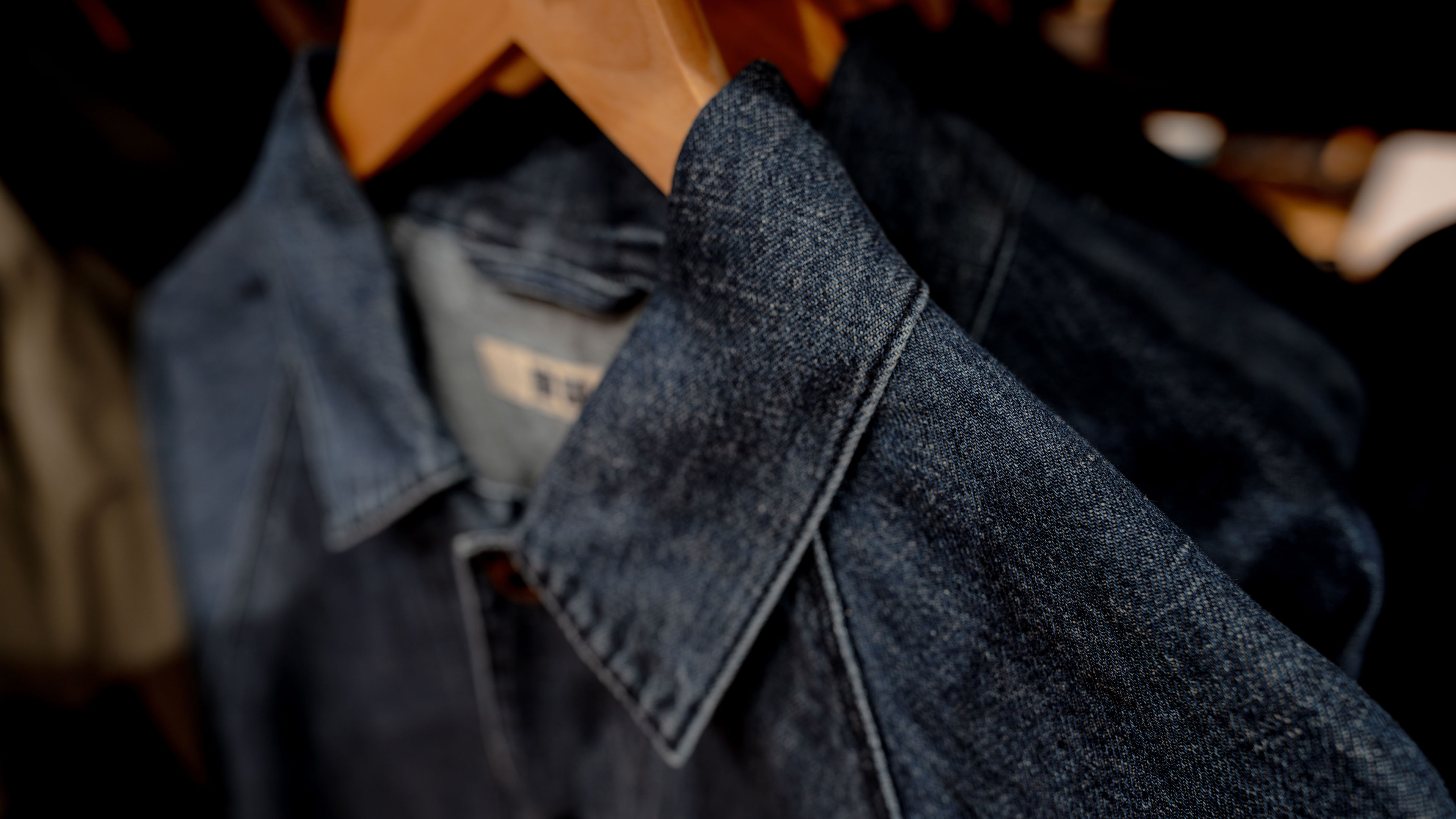 Selective focus on jacket jeans hanging on rack in clothes shop