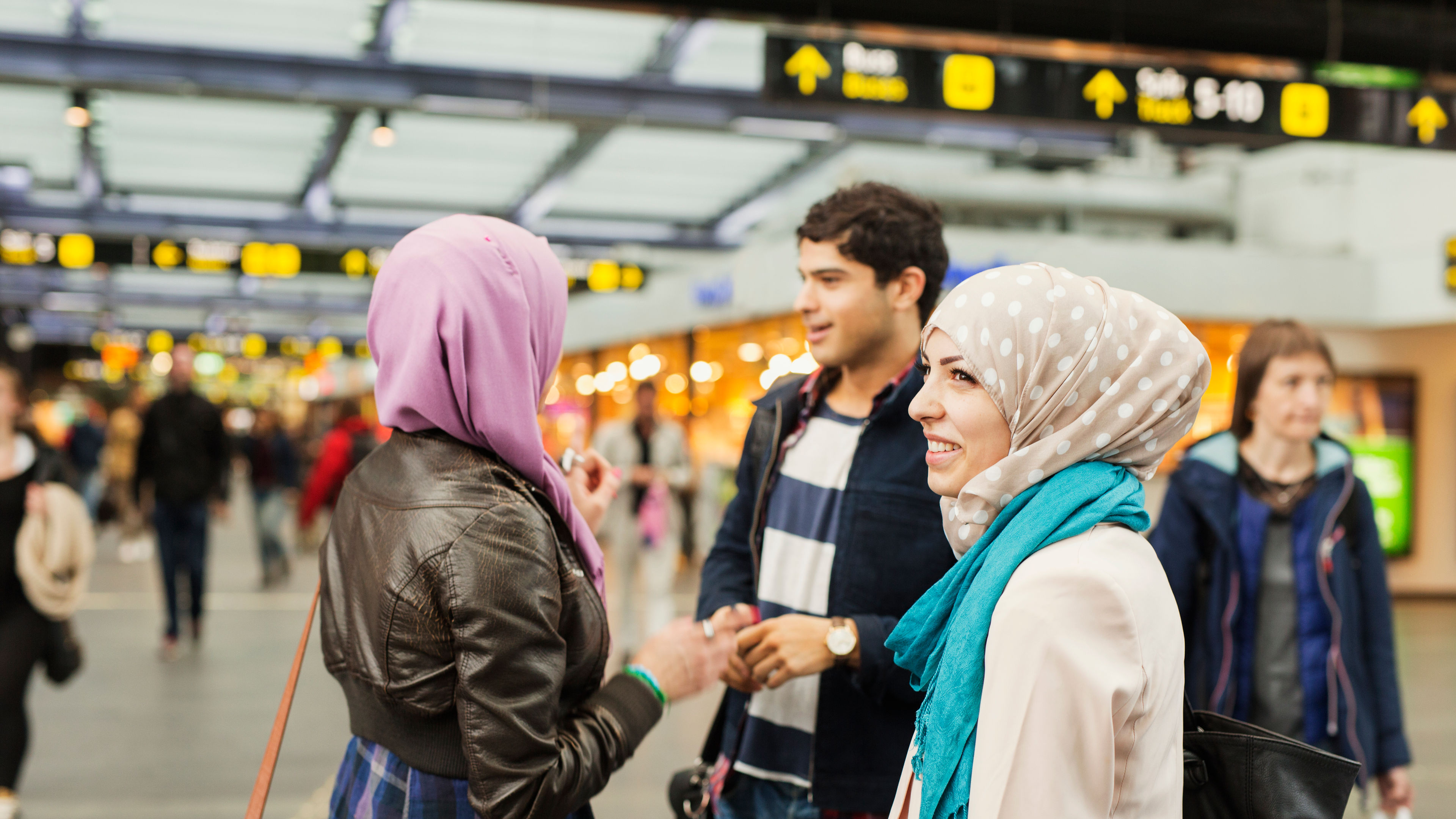 Smiling woman standing with friends at railroad station